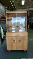 Front view of Mid-Century Modern Heywood Wakefield hutch showing glass sliding doors and wood finish.