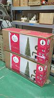 Two large boxed cartons containing the 12ft artificial Christmas tree in original packaging, showing size and brand markings.