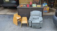 Photo showing three vintage wooden Childcraft molded plywood stacking toddler chairs and a modern gray kid's recliner chair. Vintage toy banks and collectible items sit on a dark brown outdoor storage box behind.