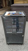 Full front view of the stacked vintage rack stereo system housed in a black cabinet with a glass door, showing multiple components inside.