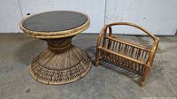 Both vintage wicker table with smoked glass top and rattan magazine rack shown together on concrete floor.