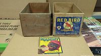 Two wooden produce crates side by side; left plain, right with Red Bird Apples label; loose Mammy label placed in front.