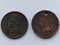 Obverse view of 1904 and 1863 Indian Head one cent coins, showing Native American head design; 1863 coin with hole near top rim.