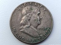 Obverse of the 1951 Franklin Half Dollar coin showing Benjamin Franklin's profile with signs of dirt and wear.