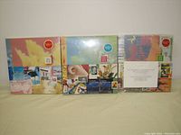 Front view of all three albums sealed in shrink-wrap, showing collage artwork and year labels with price sticker.