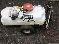 Side angle view of sprayer showing tank, frame, wheels, pump