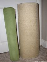 Two rolled items side by side: green mesh non-slip under pad and light brown carpet runner.