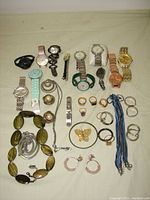 Overview of watches, rings, necklaces, bracelets, earrings, and butterfly brooch on cloth background