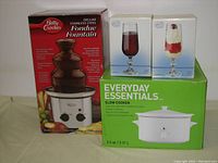 Front view showing boxed Betty Crocker Deluxe Stainless Steel Fondue Fountain, Everyday Essentials Slow Cooker, and two Bohemia Crystal flute glass boxes