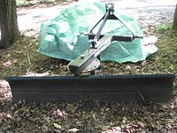 Front view of the full 72" wide black steel blade mounted on A-frame hitch assembly
