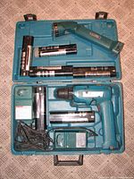 Full kit inside open blue carrying case showing cordless drill, flash light, six batteries, and two chargers