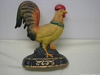 Front view of metal rooster door stop showing detailed painted finish and decorative base.