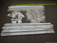 Photo showing the white drawer glides, used white cabinet hinges, and packaged new Richelieu cabinet hinges with tape measure for scale.