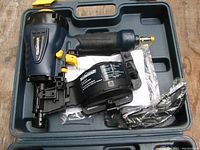 Open case showing Mastercraft coil roofing nailer, instruction manual and safety glasses