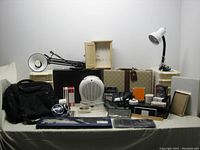 Full lot front view showing all items arranged on table including heater, briefcases, bags, lamps, and office supplies.
