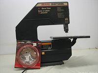 Side view of the Sears Craftsman 10 inch band saw with the new cutting blade in its original red packaging placed beside it.