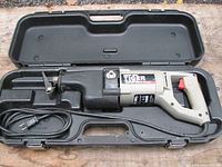 Reciprocating saw in open black hard plastic carrying case showing full tool and power cord.