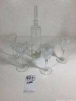 Front view of decanter with stopper and four glasses on white background