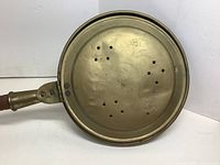 Close-up of brass lid showing perforations and decorative etchings
