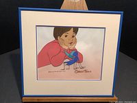 Full view of framed cel showing female character, double mat and blue frame