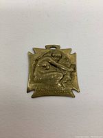 Close-up of brass Lalique Orphelinat Des Amrees medal showing seated figure, marked with text.