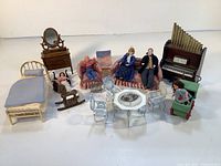 Photo showing entire set of miniature doll house furniture and dolls on white background