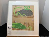 Frontal photo of framed artwork showing a green snake collage with grass and flowers on a tan background.