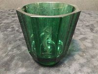 Front view showing the geometric faceted green crystal cup with etched female figure.