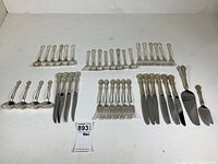 Overview of all 42 Mirrorstele flatware pieces arranged on white surface