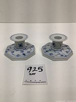 Pair of Royal Copenhagen candle holders showing front and side view with blue fluted plain pattern, octagonal base, white porcelain with blue floral motifs.
