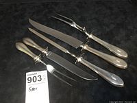 Photo of 5-piece carving and luncheon set on black background, showing knives and forks with sterling handles and metal blades/forks.