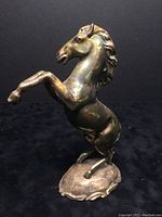 Front-left angle view of the rearing horse figurine on its base showing overall form and patina.