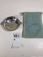 Top view of the polished sterling silver bowl with handles and Tiffany & Co. pouch to the right.