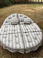 Full view of the chaise lounger with striped cushions and matching pillows on grass.