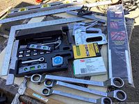 Photo showing various hand tools including levels, wrench set, staple gun with staples, and small tool kit