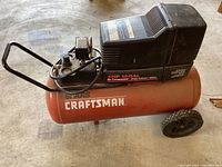 Side view showing red tank labeled '4 HP 15 GAL Air Compressor Single Cylinder / 100 PSI' with Craftsman logo, motor housing, and handle.