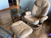 Overview of recliner, ottoman, and glass top table on hardwood floor