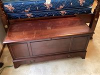Front view of closed cedar chest showing dark brown wood finish, panel details and base drawer.