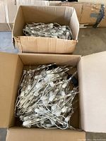 Two cardboard boxes filled with coiled white wired icicle string lights with clear plastic icicles and timer plugs, shown from above.
