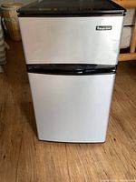 Front view of the Magic Chef mini fridge and freezer with silver door and black trims.