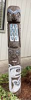 Front view of full totem pole showing all three carved figures