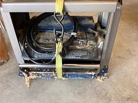 View of the Ryobi surface planer strapped down showing the electric cord and body with wood shavings around the base.