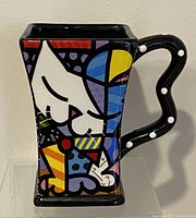 Front and side view showing colorful cat design and square shape with decorative polka dot handle.