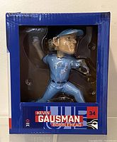 Front view of unopened Kevin Gausman bobblehead in original blue box with clear window showing bobblehead pitching pose.