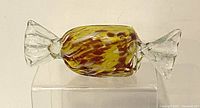 Front view of Murano art glass wrapped candy with yellow and brown swirls inside clear twisted ends