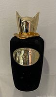 Front view of the Sospiro Opera perfume bottle showing the gold-tone plaque with logo and name on black velvet bottle.
