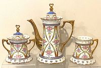 Full view of the coffee pot, creamer jug, and sugar bowl showing hand painted floral and gold detailing.