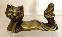 Front view of brass cat mermaid paperweight showing smiling cat face and curled mermaid tail fin
