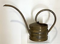 Side view of the copper watering can showing curved handle and long spout