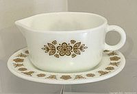 Photo of the white Pyrex gravy boat with gold floral design and matching under-plate, showing full side profile.